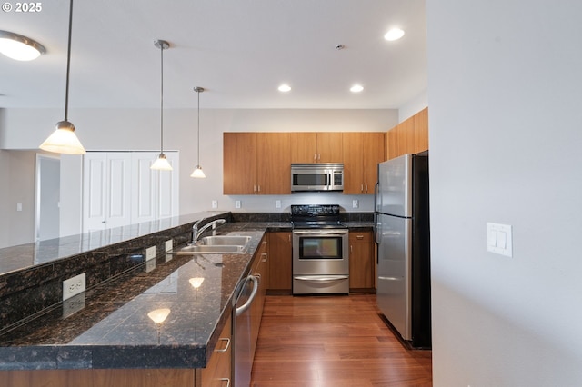 8712 N Decatur St Unit 302, Portland, OR 97203 - kitchen with stainless steel appliances, brown cabinetry, a sink, a peninsula, and dark wood finished floors