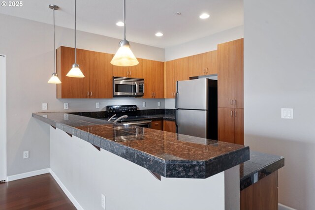 8712 N Decatur St Unit 302, Portland, OR 97203 - kitchen with appliances with stainless steel finishes, tile counters, a peninsula, brown cabinets, and a kitchen breakfast bar