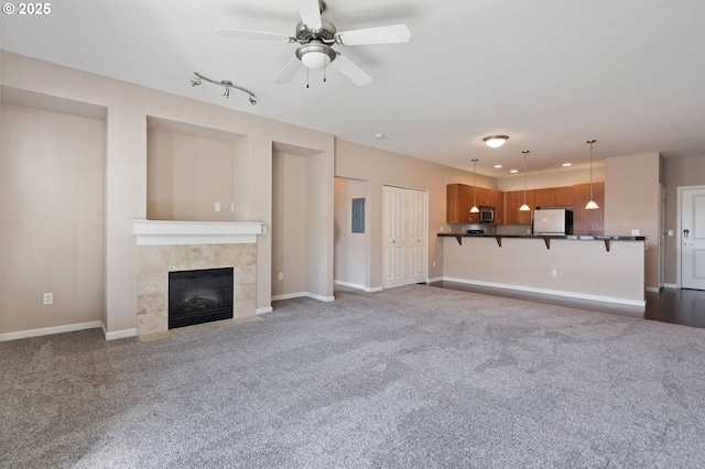 8712 N Decatur St Unit 302, Portland, OR 97203 - unfurnished living room with carpet flooring, a ceiling fan, a fireplace, and baseboards