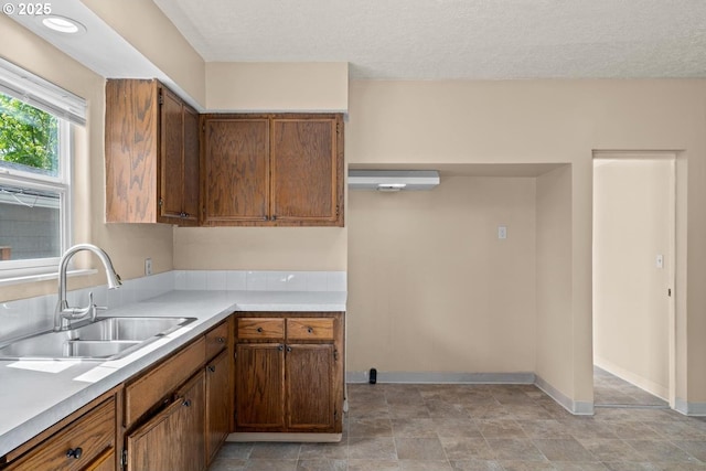 8316 SE Raymond Ct, Portland, OR 97266 - kitchen with a sink, light countertops, baseboards, brown cabinetry, and a textured ceiling