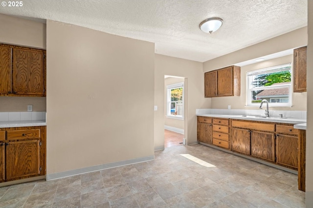8316 SE Raymond Ct, Portland, OR 97266 - kitchen featuring brown cabinets, light countertops, a sink, plenty of natural light, and a textured ceiling