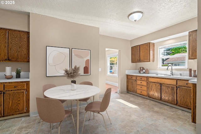 8316 SE Raymond Ct, Portland, OR 97266 - kitchen featuring brown cabinetry, light countertops, a textured ceiling, plenty of natural light, and a sink