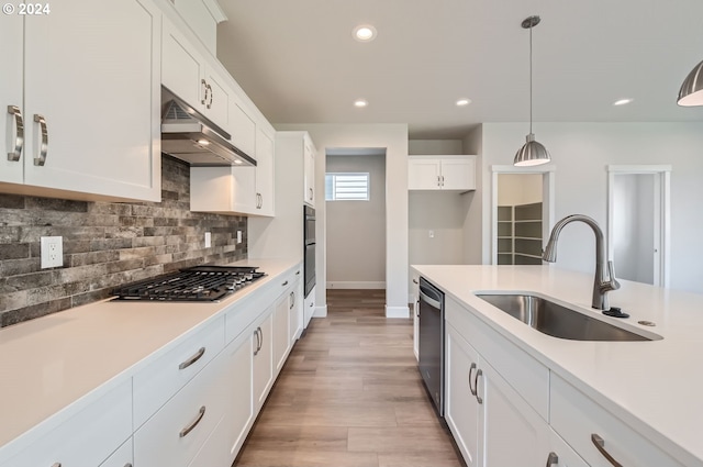 kitchen featuring stainless steel appliances, white cabinetry, hanging light fixtures, and sink