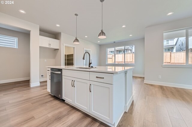 kitchen with a kitchen island with sink, pendant lighting, white cabinets, stainless steel dishwasher, and sink