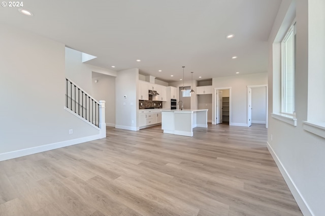 unfurnished living room with light wood-type flooring and sink