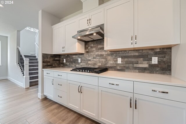 kitchen with light hardwood / wood-style flooring, white cabinetry, backsplash, and stainless steel gas cooktop