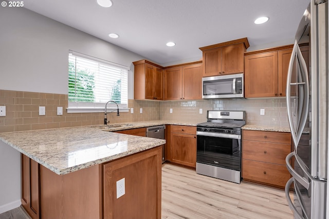 100 Running Dogs Ln, Saint Helens, OR 97051 - kitchen featuring appliances with stainless steel finishes, a sink, a peninsula, brown cabinetry, and recessed lighting