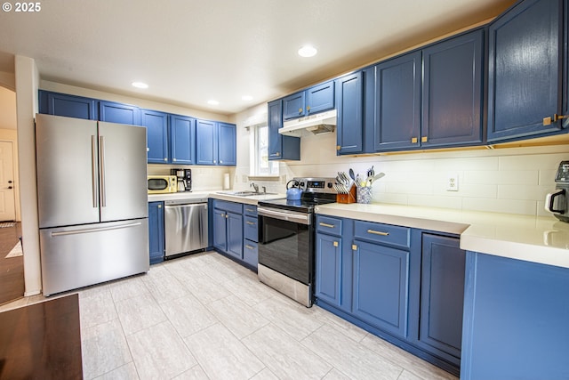 kitchen with under cabinet range hood, blue cabinetry, appliances with stainless steel finishes, and light countertops