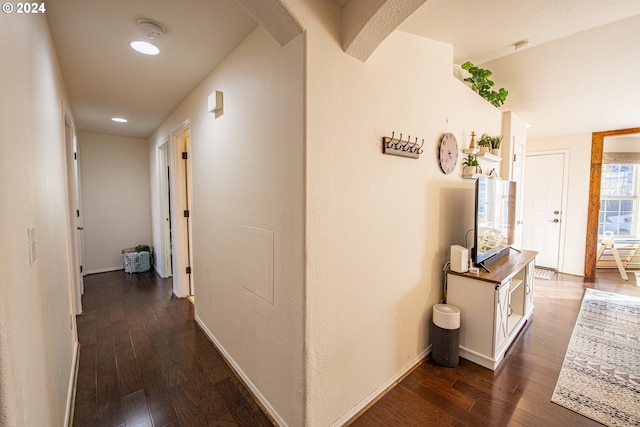 hallway with baseboards, dark wood-style flooring, and arched walkways