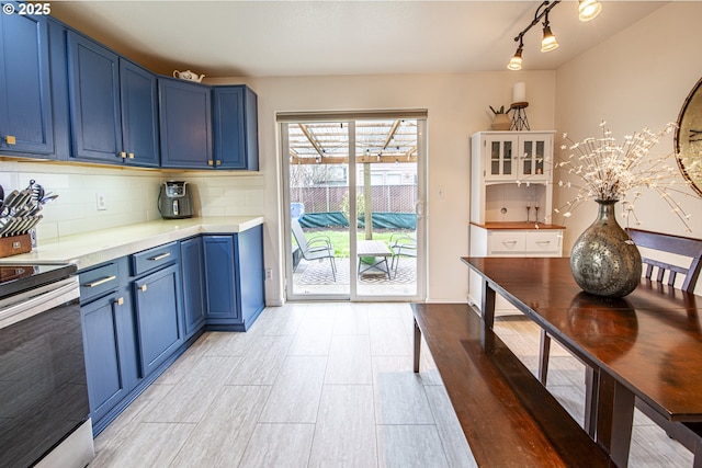 kitchen with decorative backsplash, light countertops, blue cabinetry, and electric stove