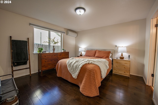 bedroom featuring baseboards, dark wood-type flooring, and an AC wall unit