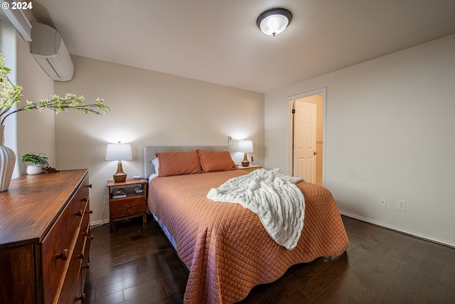 bedroom featuring dark wood-style floors, a wall mounted air conditioner, and baseboards