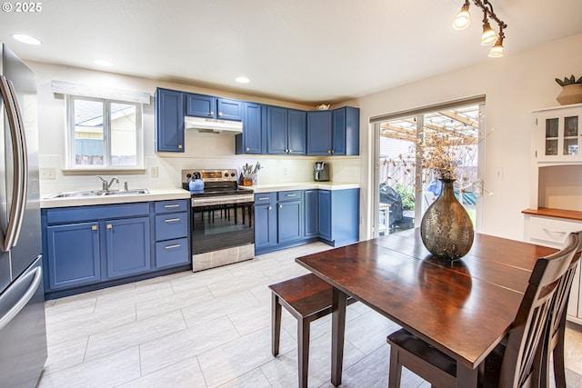 kitchen with under cabinet range hood, appliances with stainless steel finishes, blue cabinets, and a sink