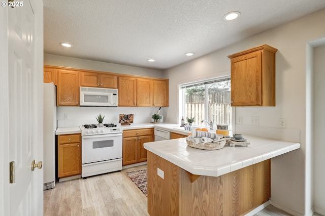 41653 NW Oak Way, Banks, OR 97106 - kitchen with white appliances, a peninsula, light wood-style floors, recessed lighting, and a textured ceiling