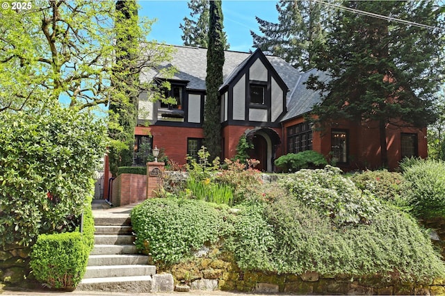 english style home with roof with shingles and brick siding