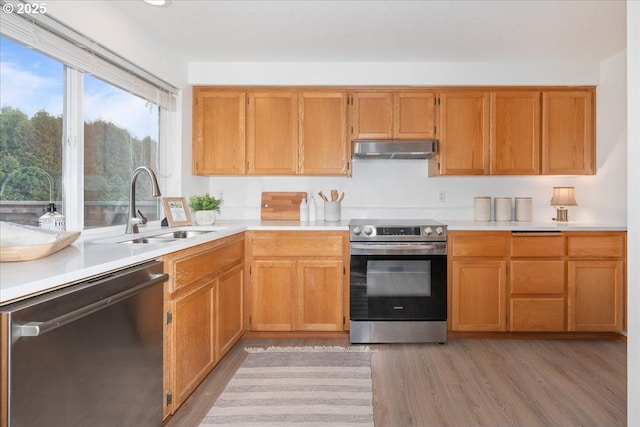 5249 NW 173rd Pl, Portland, OR 97229 - kitchen with appliances with stainless steel finishes, wall chimney exhaust hood, light countertops, and light wood-style flooring