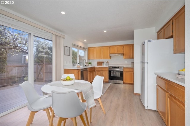 5249 NW 173rd Pl, Portland, OR 97229 - kitchen with stainless steel appliances, under cabinet range hood, light countertops, light wood-style flooring, and recessed lighting