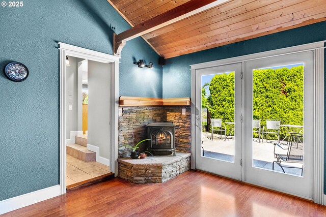 living area with wooden ceiling, plenty of natural light, a wood stove, wood finished floors, and a textured wall