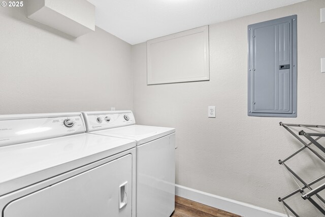 laundry room with electric panel, washer and clothes dryer, wood finished floors, and baseboards