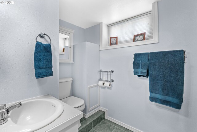 bathroom with a sink, toilet, tile patterned floors, and baseboards