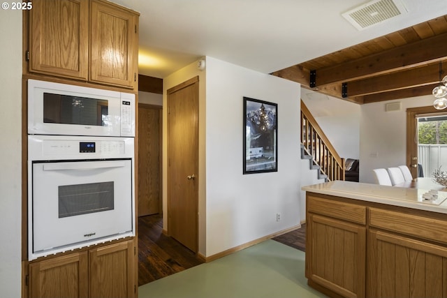 17692 Rogue Ln, Sunriver, OR 97707 - kitchen featuring white appliances, brown cabinetry, light countertops, dark wood-style flooring, and baseboards
