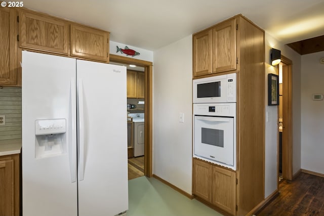 17692 Rogue Ln, Sunriver, OR 97707 - kitchen featuring white appliances, dark wood-style flooring, washer / dryer, baseboards, and brown cabinets