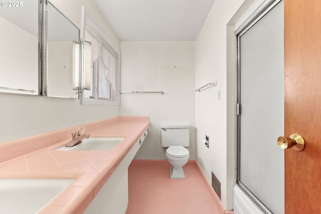 full bathroom with toilet, an enclosed shower, baseboards, double vanity, and tile patterned floors