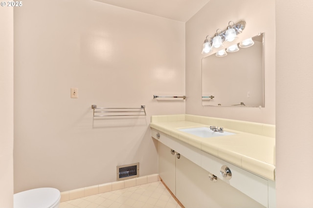 half bathroom with toilet, baseboards, vanity, and tile patterned flooring