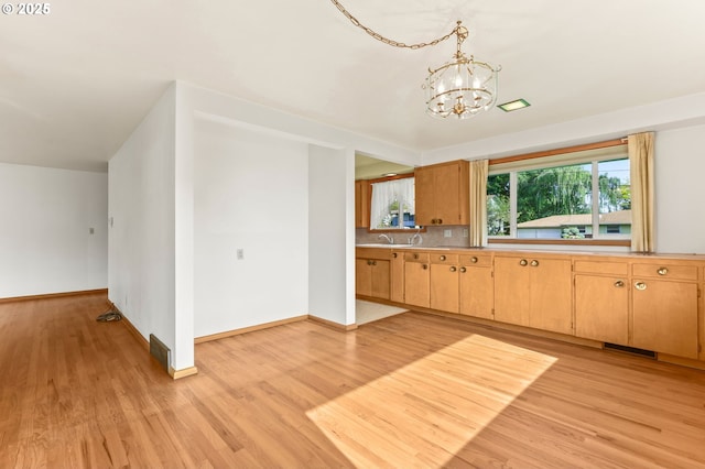 kitchen with a chandelier, light wood-style flooring, baseboards, and light countertops