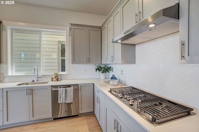17955 SW Howlock Ln, Beaverton, OR 97007 - kitchen with appliances with stainless steel finishes, under cabinet range hood, a sink, gray cabinets, and backsplash