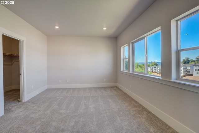 17955 SW Howlock Ln, Beaverton, OR 97007 - unfurnished bedroom featuring a walk in closet, light carpet, recessed lighting, and baseboards