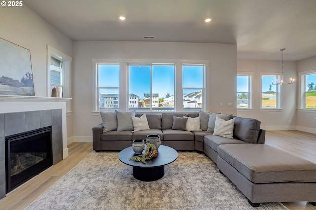 17955 SW Howlock Ln, Beaverton, OR 97007 - living area with wood finished floors, a chandelier, healthy amount of natural light, a tiled fireplace, and recessed lighting