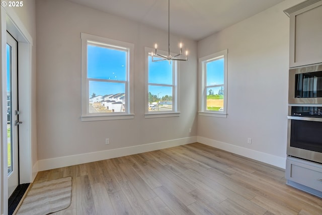 17955 SW Howlock Ln, Beaverton, OR 97007 - unfurnished dining area with light wood-style floors, a chandelier, and baseboards