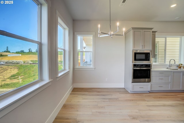17955 SW Howlock Ln, Beaverton, OR 97007 - kitchen with stainless steel oven, black microwave, a chandelier, plenty of natural light, and recessed lighting