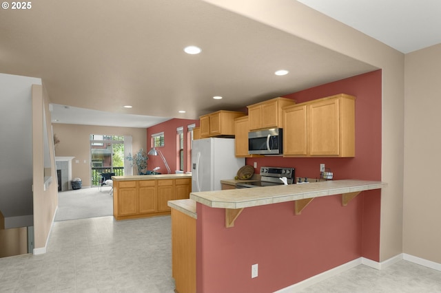 1544 SW 175th Ave, Beaverton, OR 97003 - kitchen with stainless steel appliances, a peninsula, a breakfast bar, recessed lighting, and tile countertops