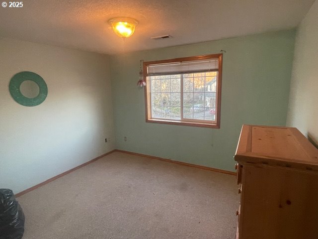 unfurnished bedroom with carpet floors, visible vents, and baseboards