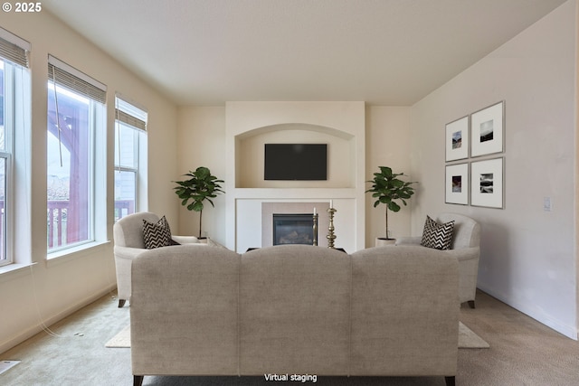 living room with a glass covered fireplace, baseboards, and light carpet