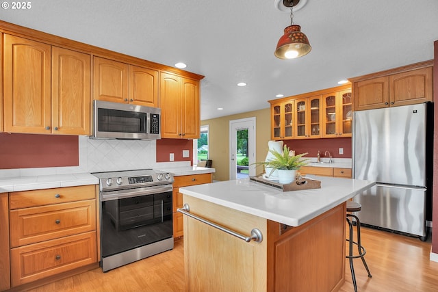 3270 N Maple St, Canby, OR 97013 - kitchen featuring appliances with stainless steel finishes, light wood-style floors, recessed lighting, glass insert cabinets, and light countertops