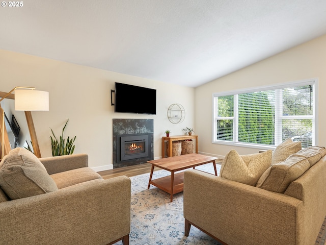 living area with baseboards, vaulted ceiling, light wood-style flooring, and a tile fireplace