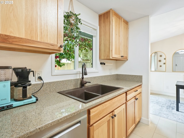 kitchen featuring light stone counters, a sink, light tile patterned floors, and light brown cabinetry