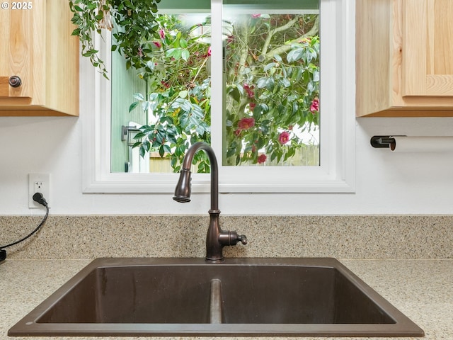 interior details with a sink, light brown cabinets, and light countertops