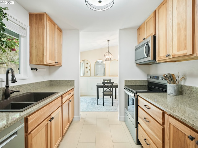 kitchen with a sink, light brown cabinetry, light stone countertops, and stainless steel appliances