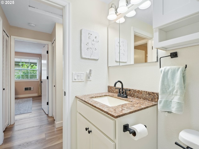 bathroom featuring visible vents, wood finished floors, vanity, baseboards, and an inviting chandelier