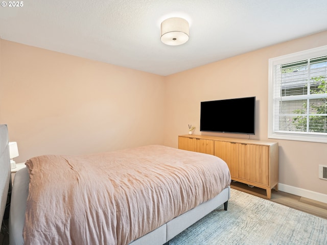 bedroom featuring baseboards, visible vents, and wood finished floors