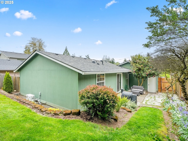 rear view of property featuring a lawn, fence, a shingled roof, and a patio area