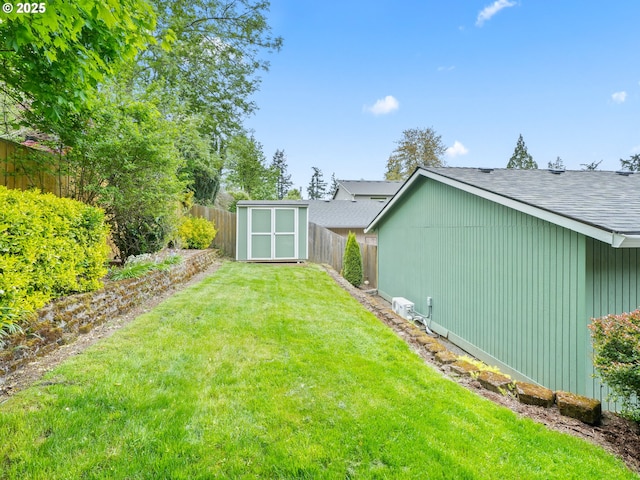 view of yard featuring an outdoor structure, a fenced backyard, and a storage unit
