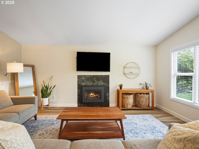 living room with baseboards, a tiled fireplace, and wood finished floors