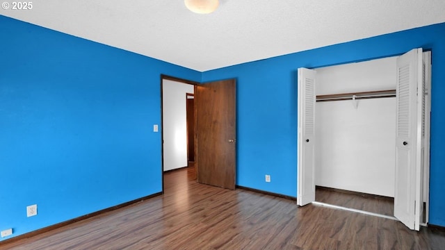 unfurnished bedroom featuring dark wood-type flooring, a textured ceiling, and a closet