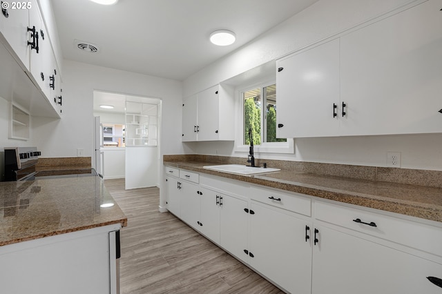 116 SE 153rd Ave, Portland, OR 97233 - kitchen with a sink, electric stove, white cabinetry, light wood-style flooring, and dark stone counters