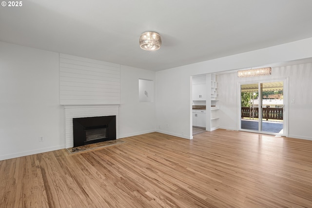116 SE 153rd Ave, Portland, OR 97233 - unfurnished living room with a chandelier, light wood-style floors, a fireplace with flush hearth, and baseboards